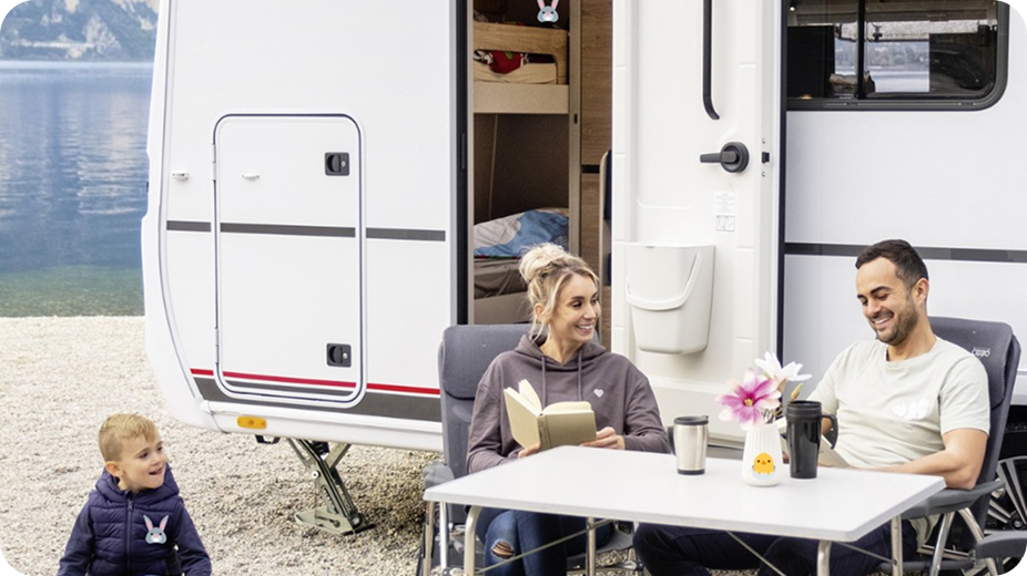 Rodzina nad jeziorem przy przyczepie kempingowej